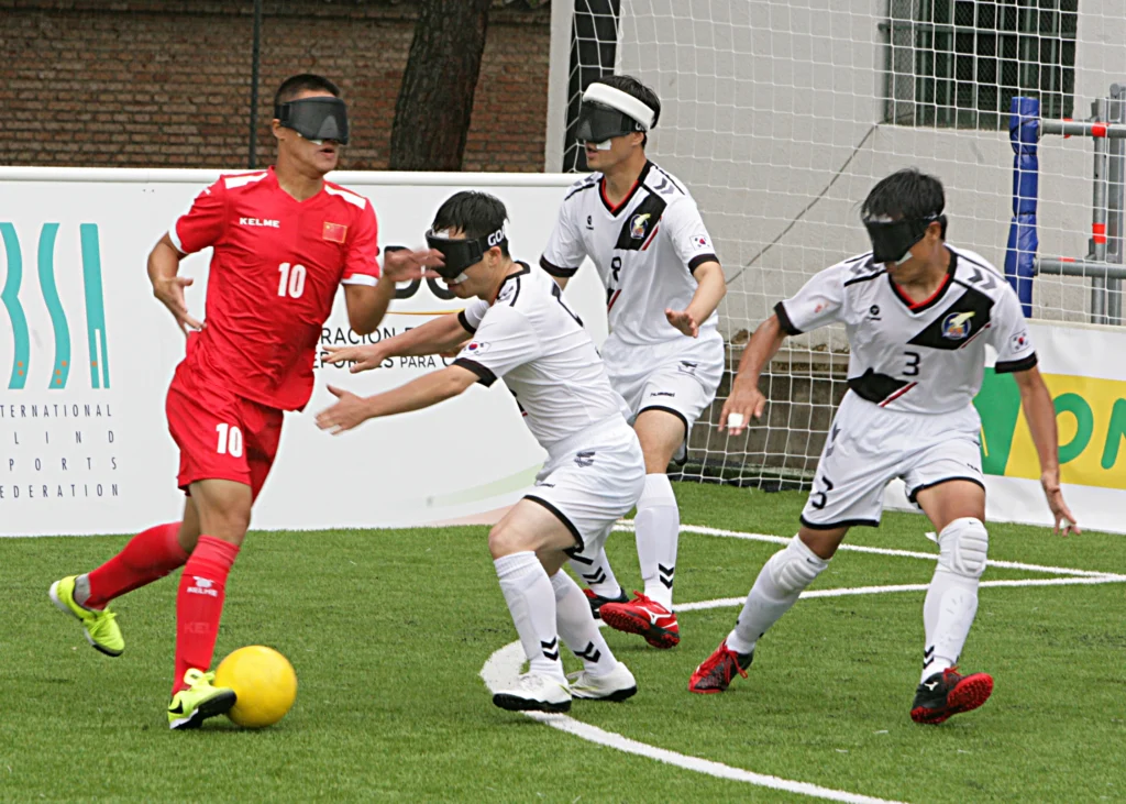 Visually impaired men playing blind football in the field